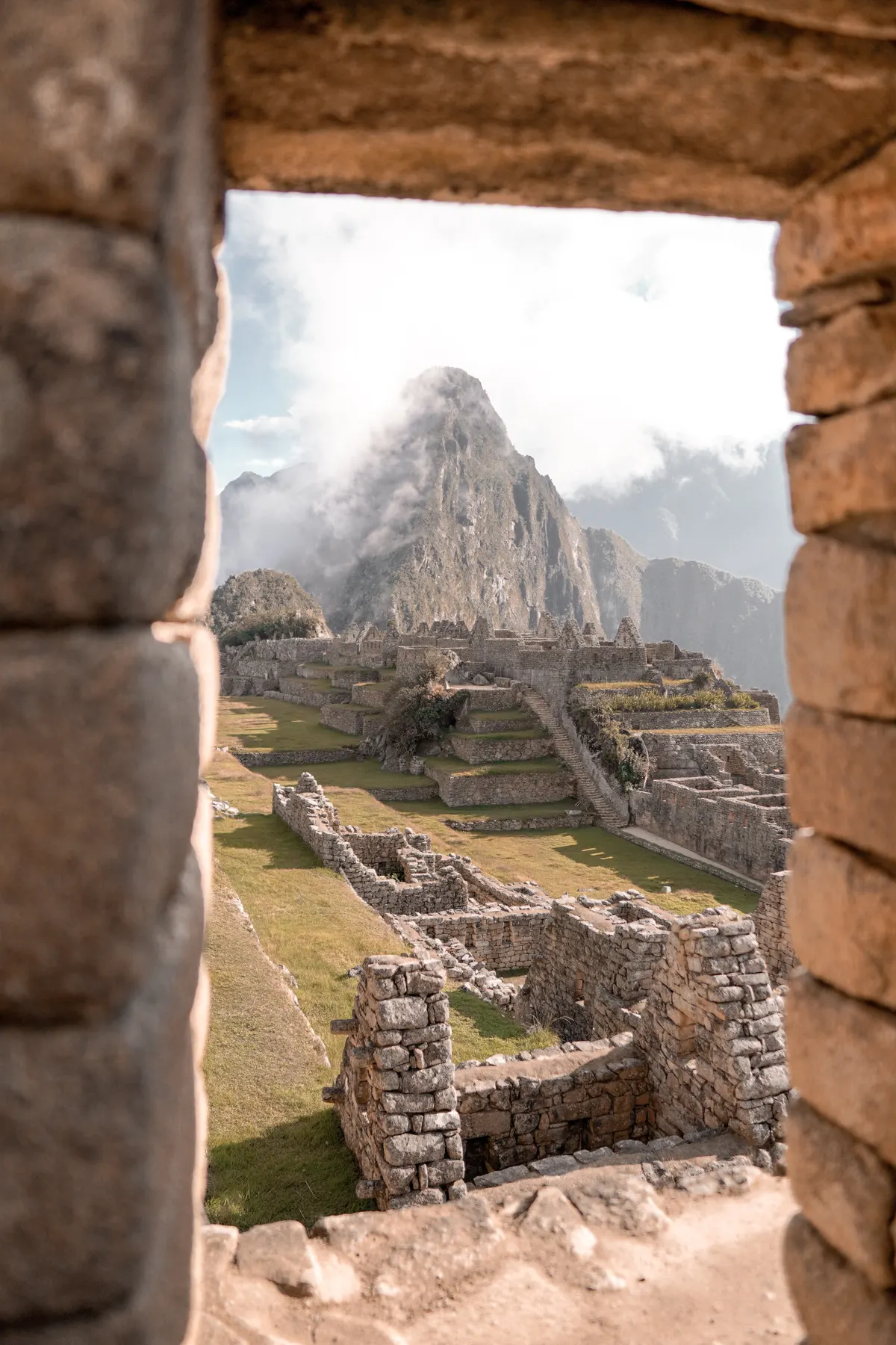 Machu Picchu ruins framed through an ancient stone window with Huayna Picchu mountain in the background